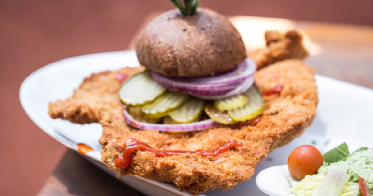 Oversized comfort pork tenderloin sandwich with pickles, onions, and rustic bun at Hash House A Go Go in Las Vegas