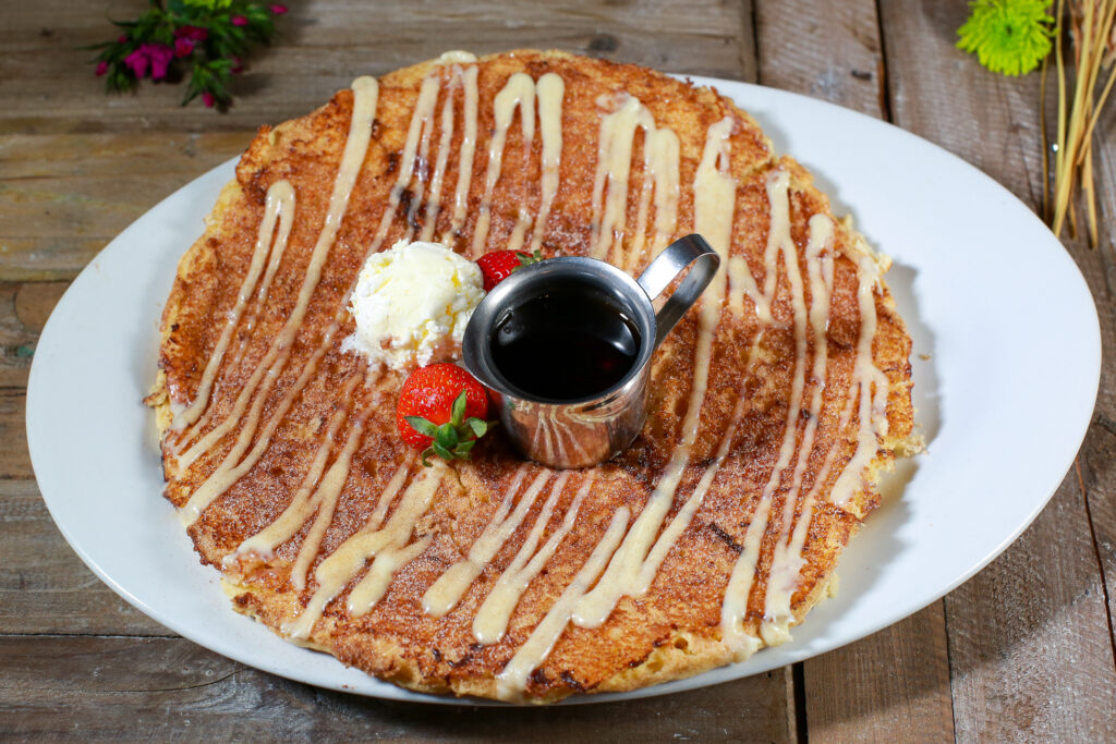 What to Expect When Dining at Hash House A Go Go in Las Vegas 1 Cinnamon roll pancake served with syrup, whipped butter, and strawberries at Hash House A Go Go, capturing a unique Las Vegas dining experience.