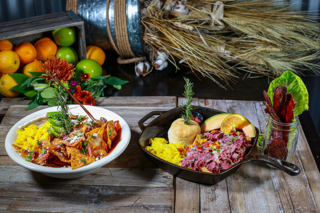 Brunch spread at Hash House A Go Go in Las Vegas featuring scrambled eggs, chilaquiles, corned beef hash, biscuit, candied bacon, and fresh fruit.