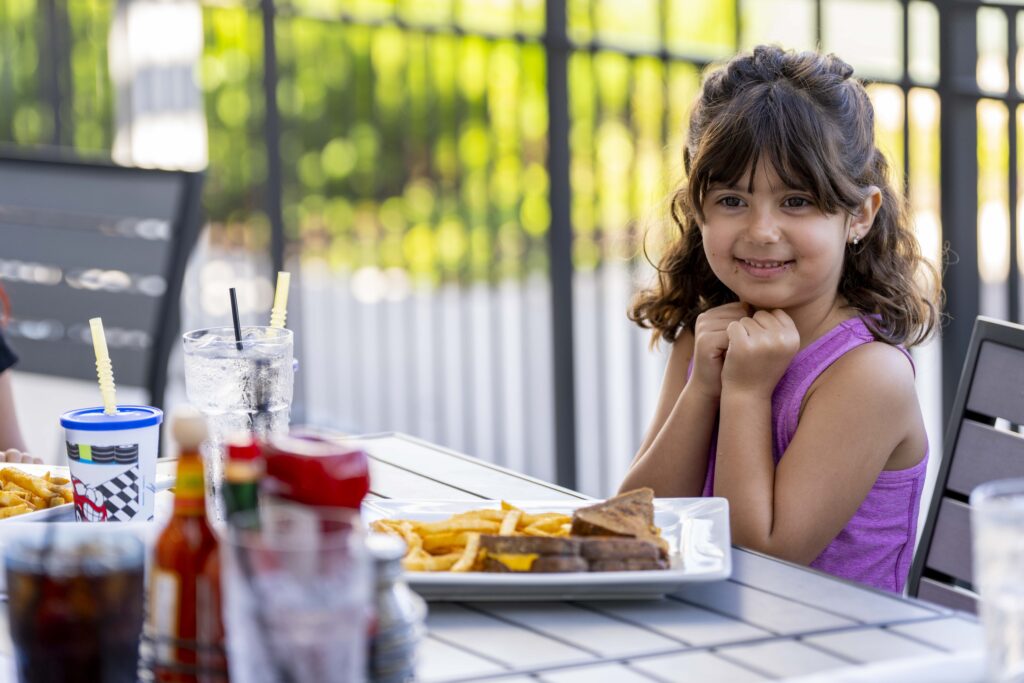 Smiling child enjoying a family meal with grilled cheese and fries at Hash House A Go Go in Las Vegas, showcasing a kid-friendly and welcoming atmosphere.
