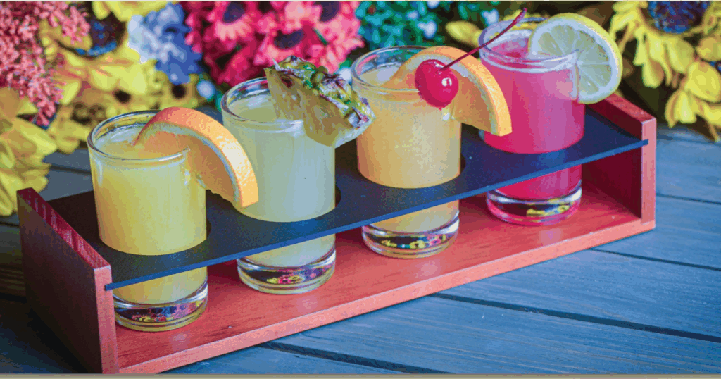 Colorful mimosa flight served at Hash House A Go Go West Sahara with tropical garnishes and floral backdrop