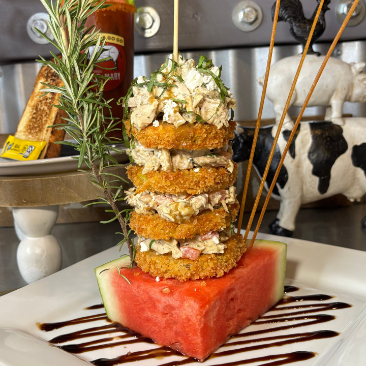 Fried green tomato stack layered with homemade chicken salad and goat cheese served on a watermelon wedge at Hash House A Go Go
