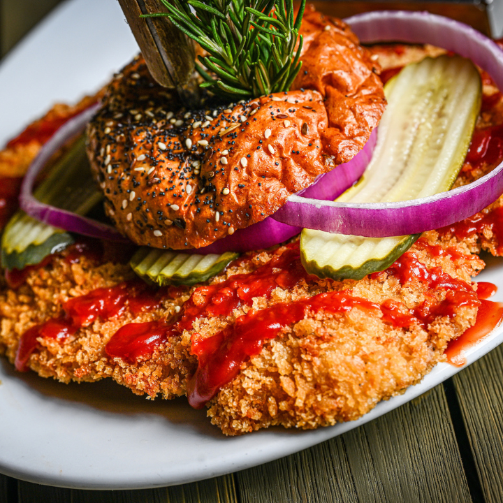 20th Anniversary pork tenderloin sandwich at Hash House A Go Go with pickles, red onion, ketchup, and a seeded bun.