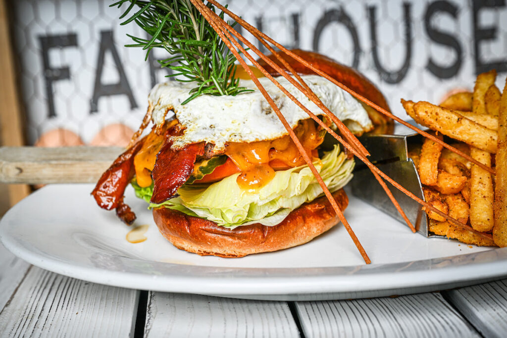 Limited-Time Fall Menu at Hash House A Go Go West Sahara 1 Fall menu featuring the hangover Burger stacked with bacon, cheddar, lettuce, tomato, and egg, served with fries at Hash House A Go Go West Sahara in Las Vegas.